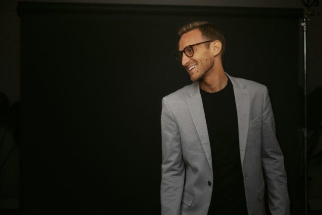 Un uomo in giacca e occhiali sorridente e soddisfatto