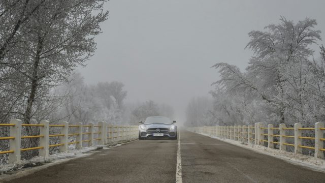 Mercedes su una strada che attraversa degli alberi innevati.